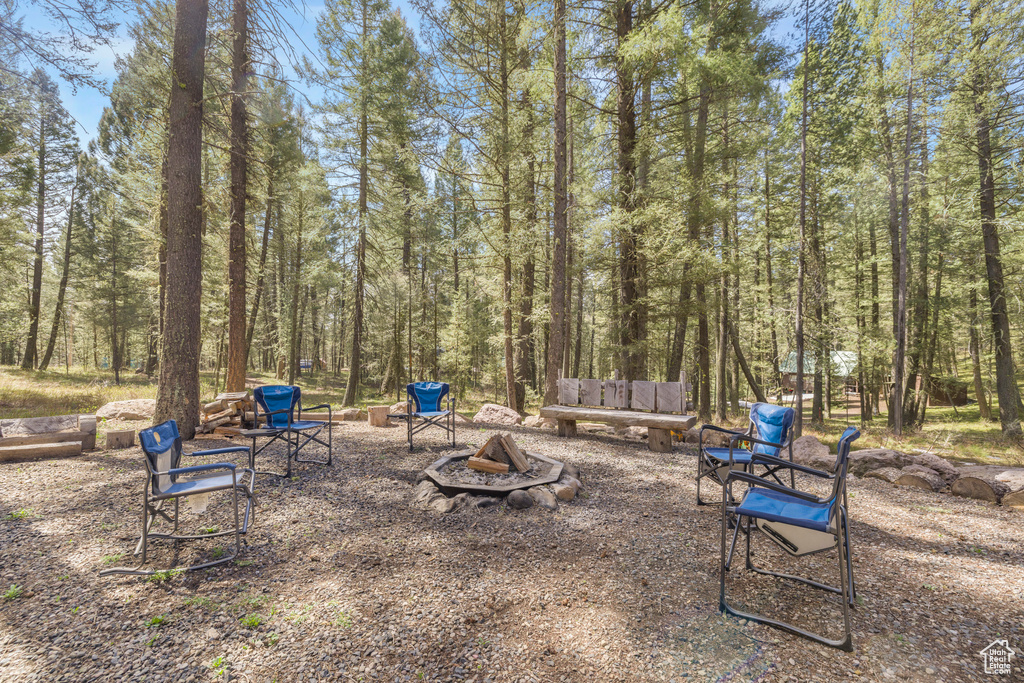 View of yard featuring an outdoor fire pit and a wooded view