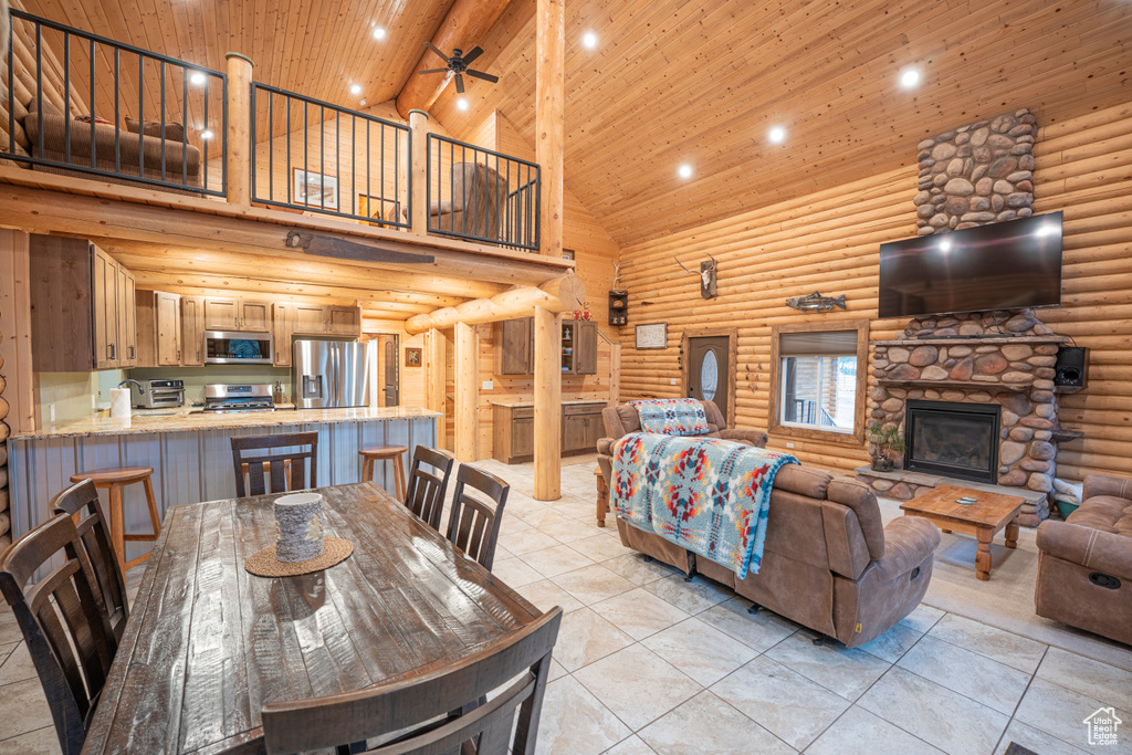 Living area with high vaulted ceiling, a stone fireplace, a ceiling fan, wood ceiling, and log walls