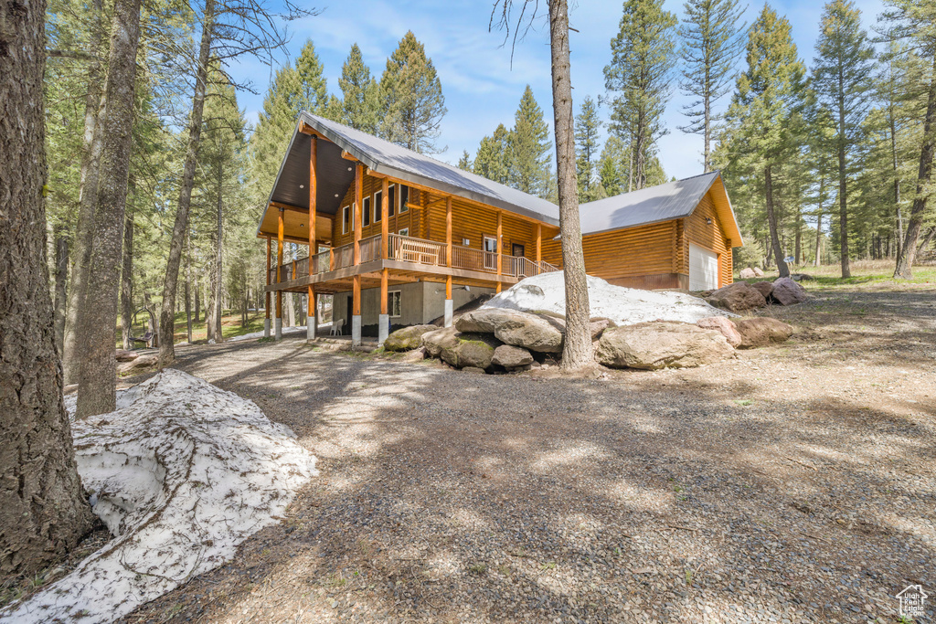 View of home's exterior featuring a wooden deck, log exterior, and a garage