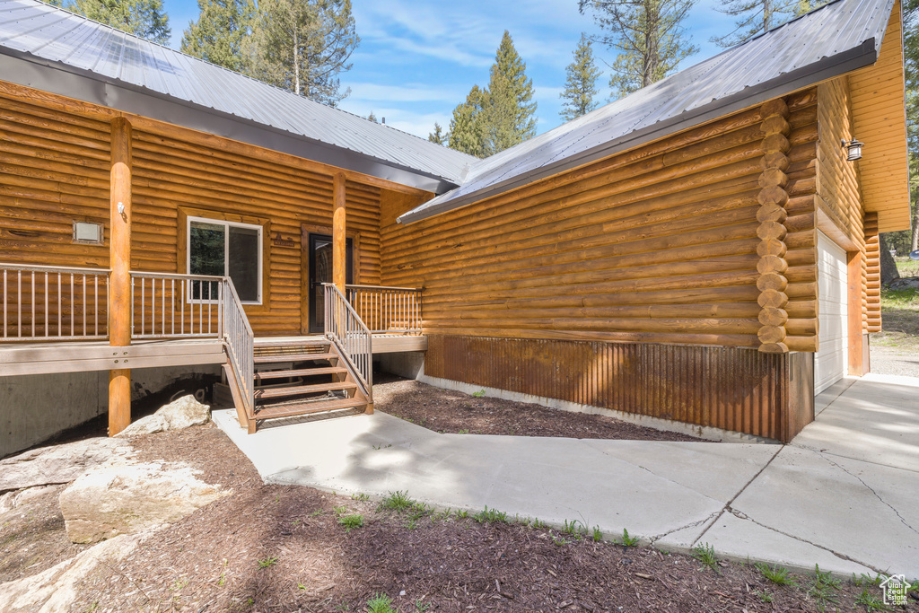 Property entrance with metal roof, a garage, and log exterior