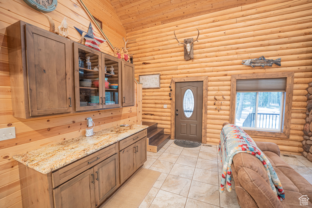 Interior space featuring light tile patterned floors, high vaulted ceiling, rustic walls, and wood ceiling