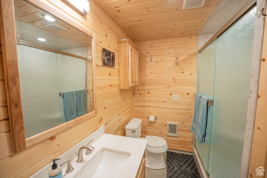 Bathroom with a shower stall, wood walls, toilet, and visible vents