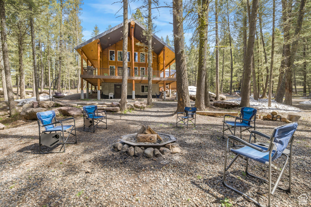 Back of property with a fire pit, a wooden deck, log veneer siding, and stairs