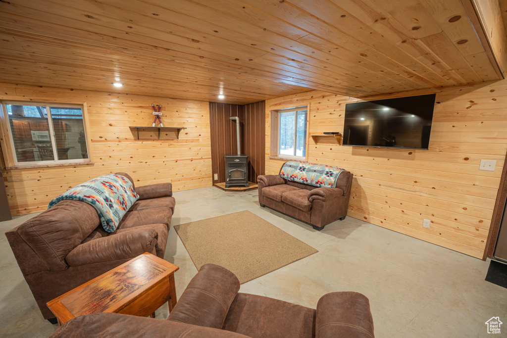 Living area with wooden walls, wooden ceiling, and a wood stove