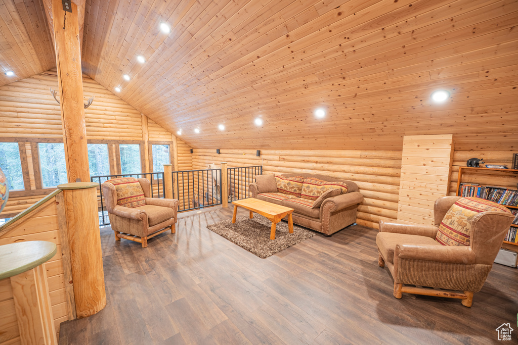 Living area with log walls, beam ceiling, wood finished floors, high vaulted ceiling, and wood ceiling