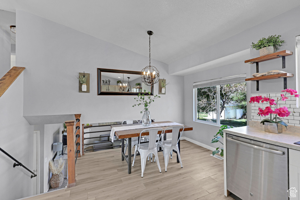 Dining space with light wood-style floors, baseboards, a chandelier, and vaulted ceiling