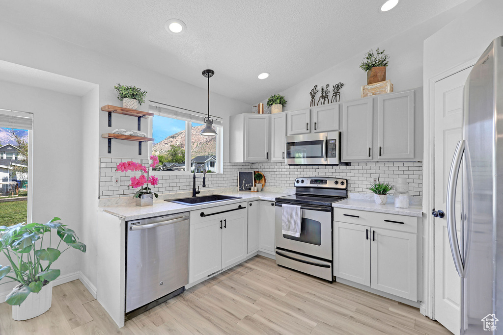Kitchen featuring a sink, tasteful backsplash, light wood-style floors, and stainless steel appliances