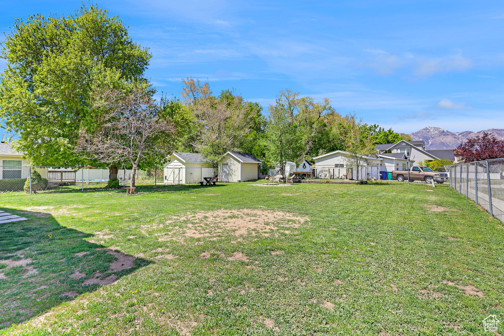 View of yard featuring a fenced backyard, a storage unit, an outbuilding, and a garage