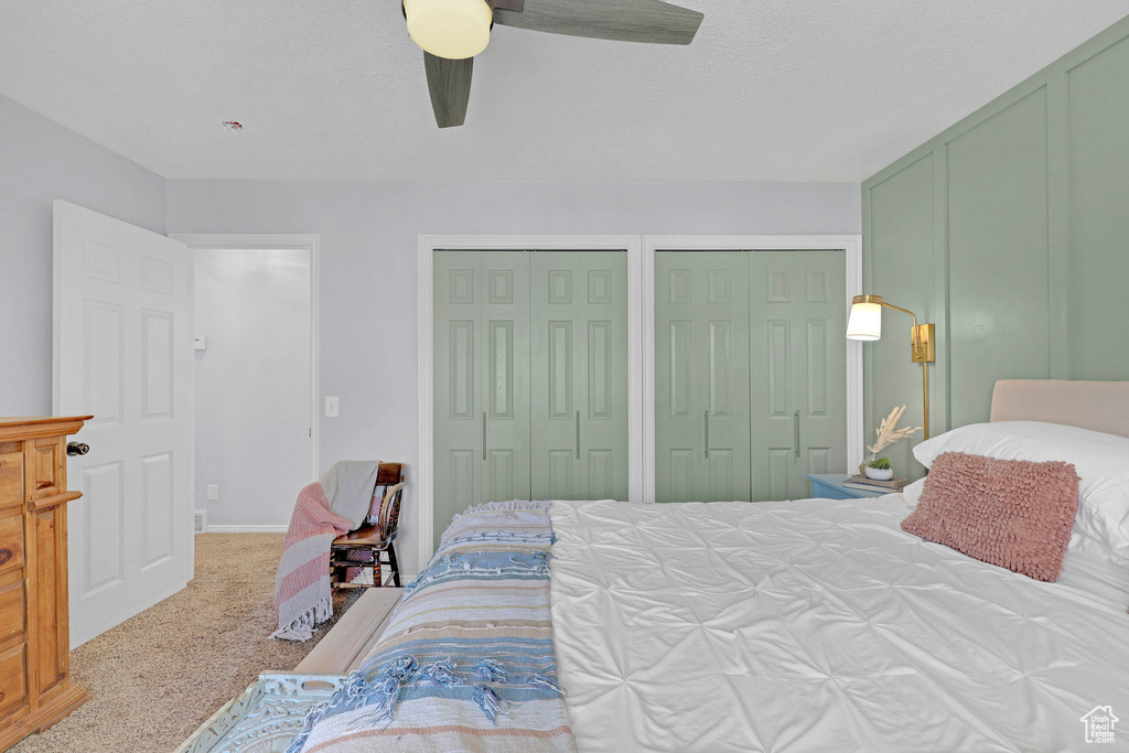 Carpeted bedroom with a ceiling fan and two closets
