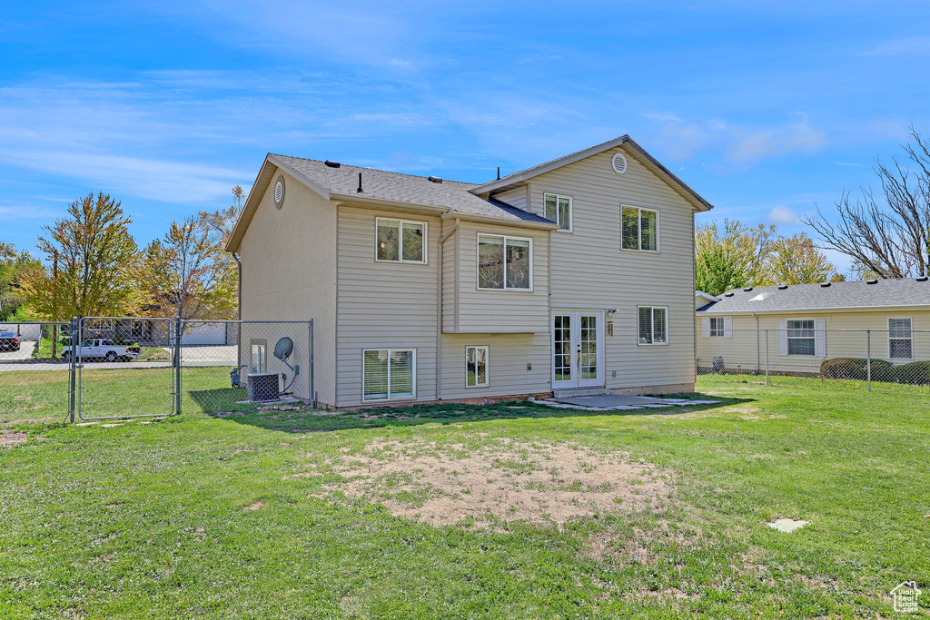 Rear view of house featuring a lawn, a gate, a fenced backyard, and french doors
