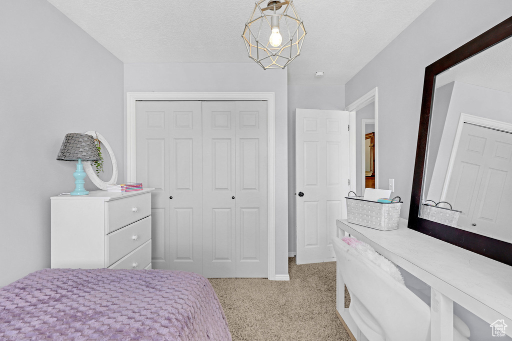Bedroom featuring baseboards, a closet, a textured ceiling, and light colored carpet