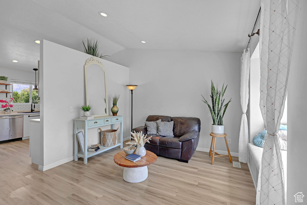Living area with visible vents, lofted ceiling, baseboards, recessed lighting, and light wood-style flooring