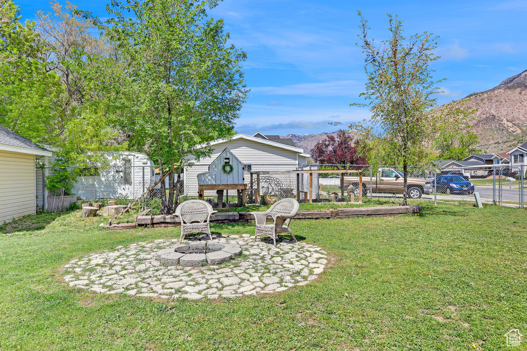 View of yard with a mountain view, fence, and an outdoor fire pit
