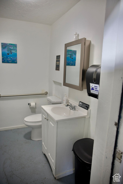 Half bath featuring vanity, baseboards, and toilet