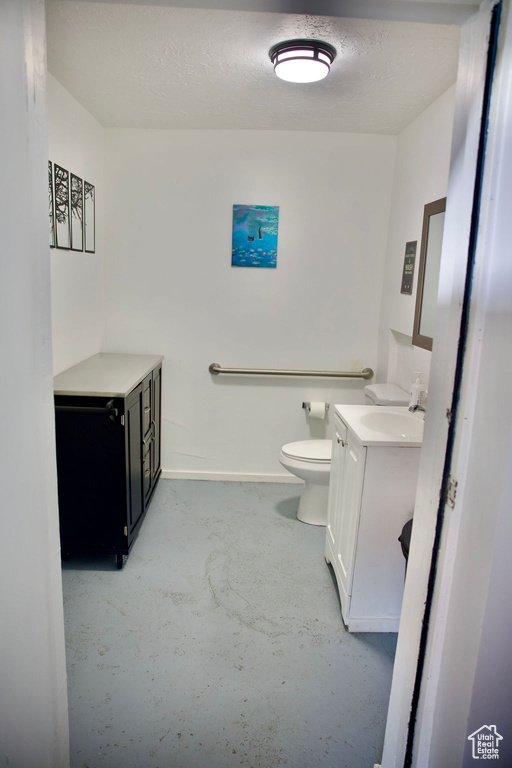 Bathroom with vanity, baseboards, concrete flooring, and toilet