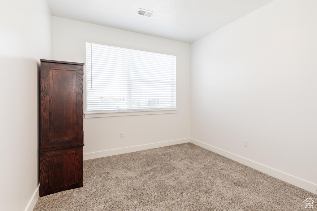 Carpeted spare room with visible vents and baseboards