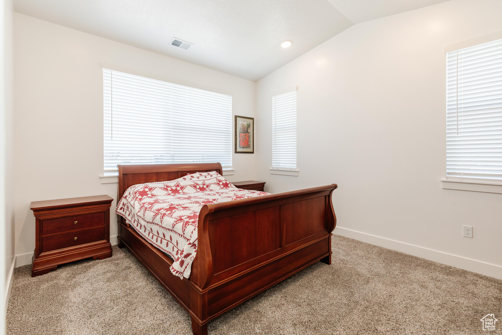 Bedroom featuring carpet flooring, vaulted ceiling, multiple windows, and visible vents