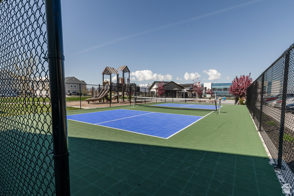 View of tennis court with fence and playground community