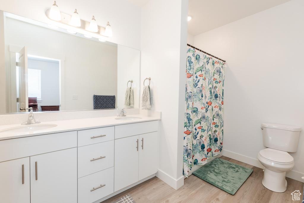 Bathroom with a sink, double vanity, toilet, and wood finished floors