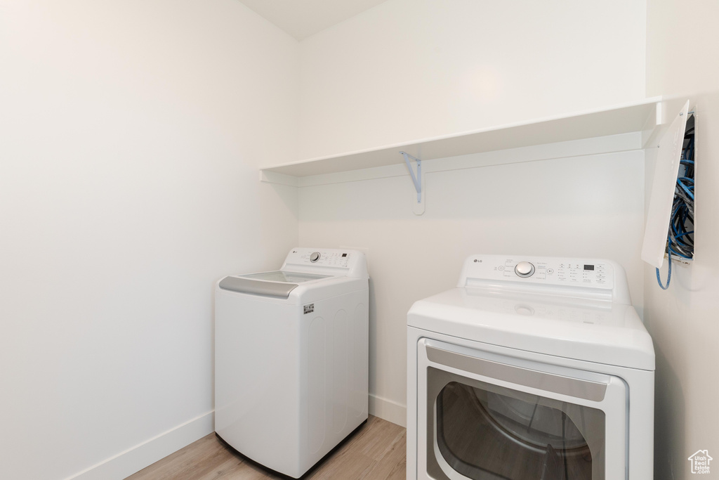 Laundry room with laundry area, light wood-style floors, baseboards, and washer and dryer