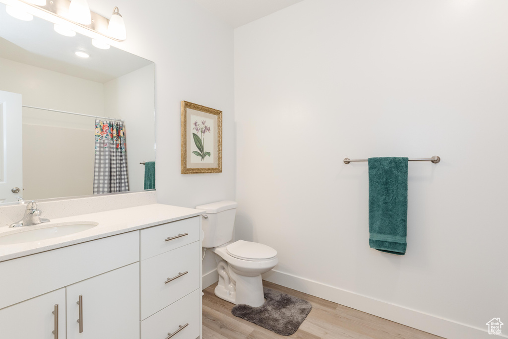 Full bath with vanity, wood finished floors, toilet, baseboards, and a shower with curtain