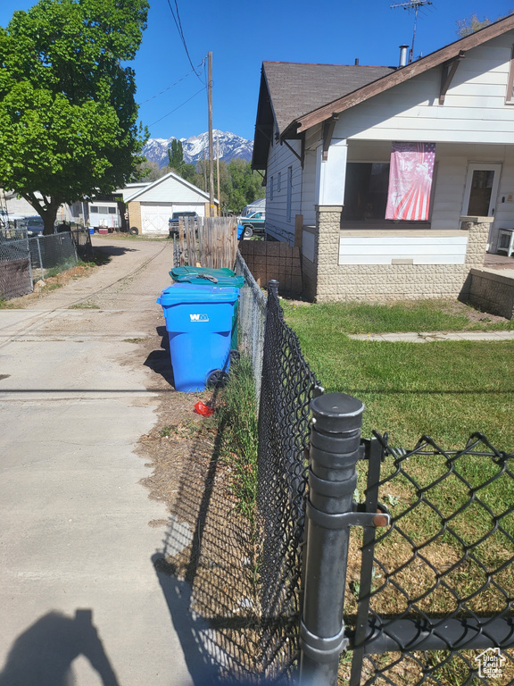 View of property exterior with fence, a detached garage, a mountain view, and driveway