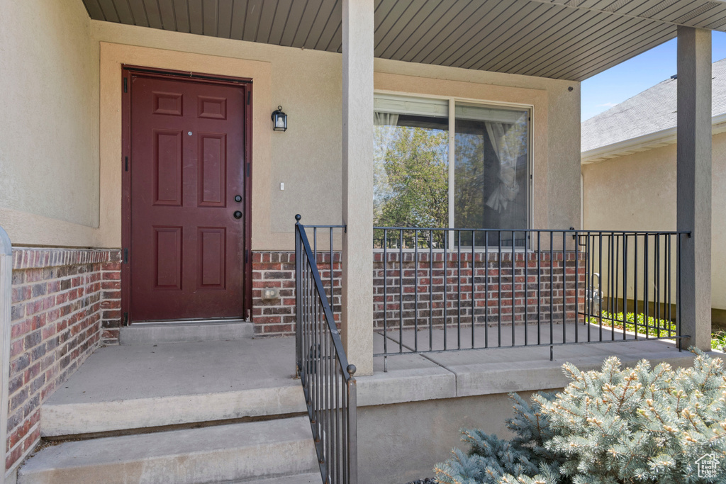 Property entrance with brick siding, stucco siding, and a porch