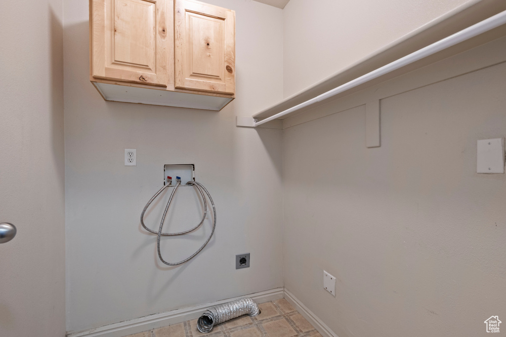 Clothes washing area featuring baseboards, hookup for an electric dryer, hookup for a washing machine, and cabinet space