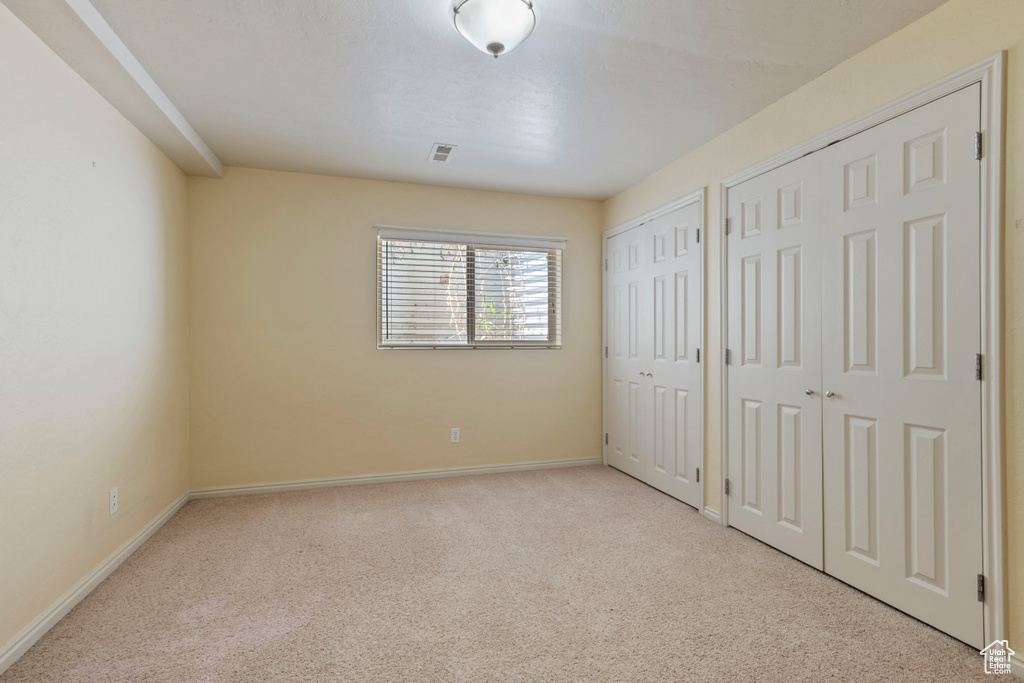 Unfurnished bedroom with multiple closets, baseboards, carpet, and visible vents