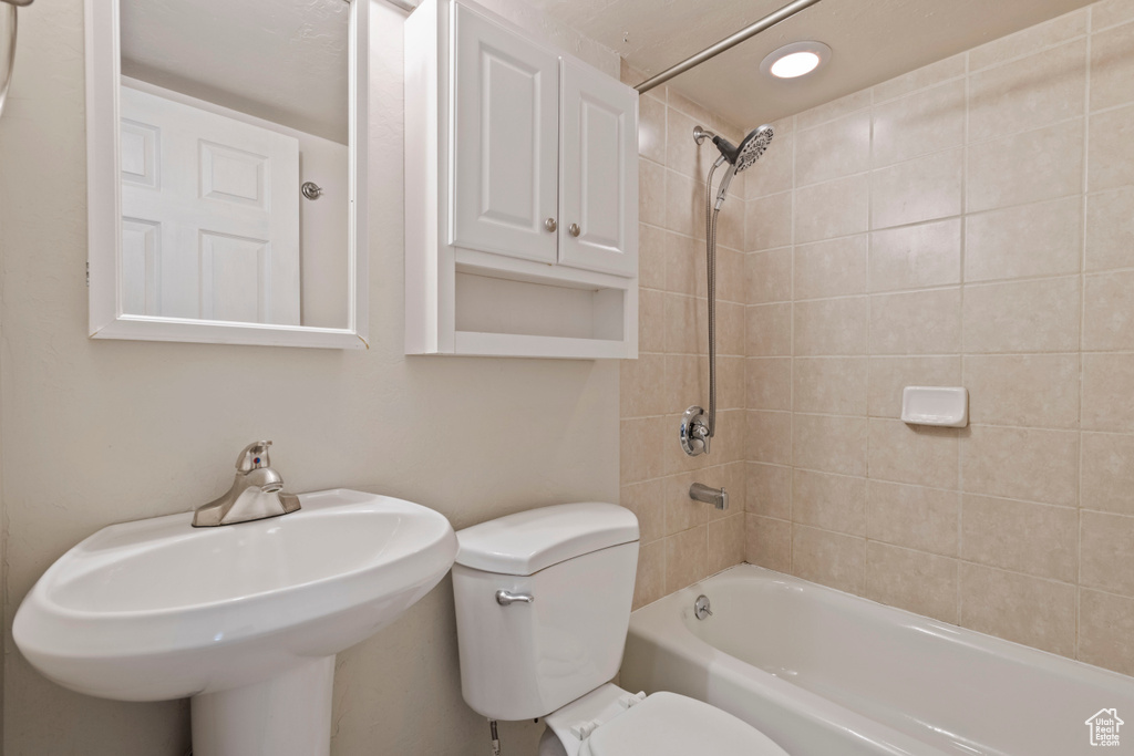 Bathroom featuring toilet, shower / washtub combination, and a sink