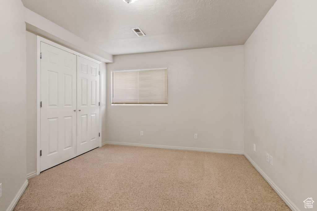 Unfurnished bedroom with visible vents, carpet, baseboards, and a closet