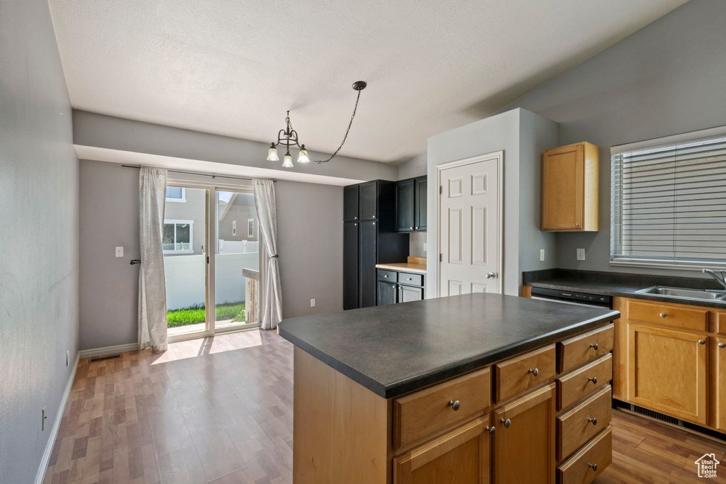Kitchen featuring dark countertops, an inviting chandelier, a sink, and wood finished floors