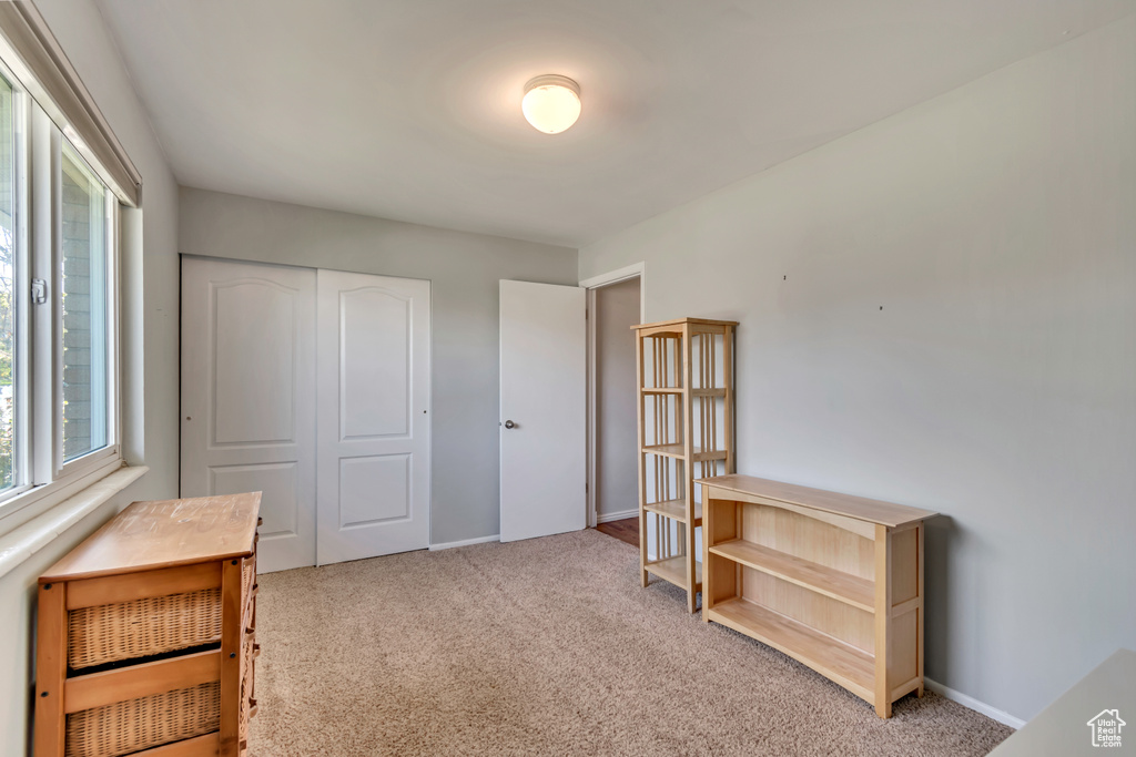 Bedroom featuring baseboards, light carpet, and a closet