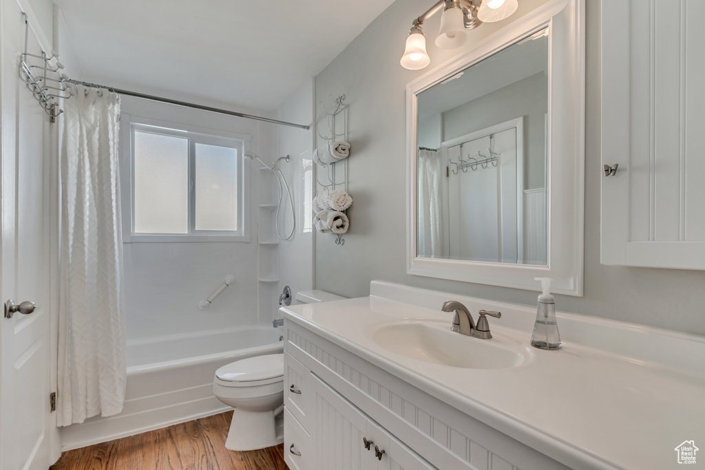 Full bath featuring vanity, shower / bath combo with shower curtain, toilet, and wood finished floors