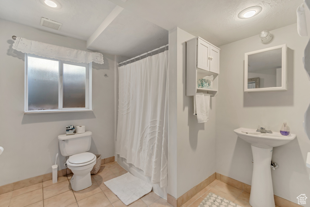 Full bath featuring toilet, baseboards, visible vents, and tile patterned flooring