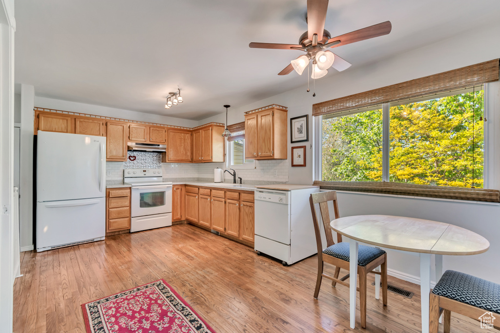 Kitchen featuring decorative backsplash, white appliances, light countertops, under cabinet range hood, and a ceiling fan