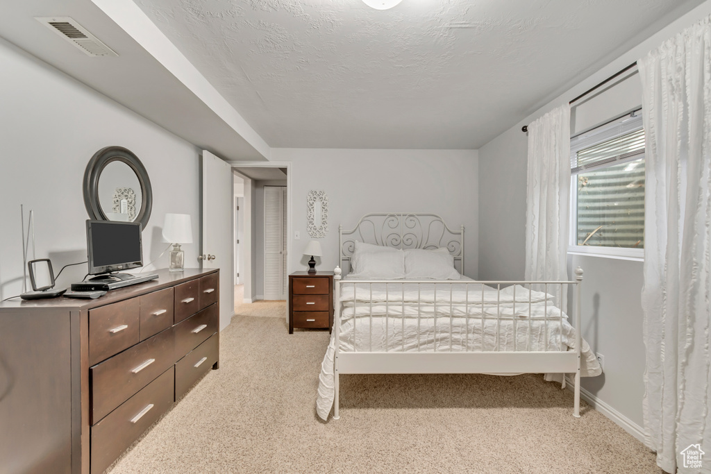Bedroom with visible vents, a textured ceiling, baseboards, and light colored carpet