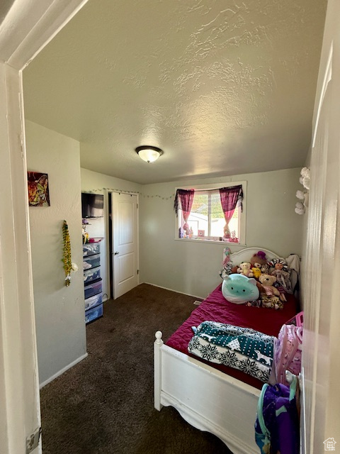 Bedroom featuring dark carpet and a textured ceiling