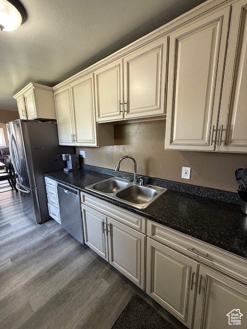 Kitchen featuring appliances with stainless steel finishes, dark wood finished floors, dark countertops, and cream cabinetry