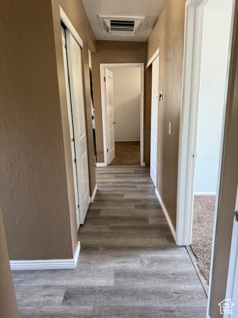 Hall with a textured wall and wood finished floors