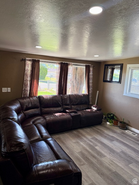Living room featuring recessed lighting, a textured ceiling, visible vents, and wood finished floors