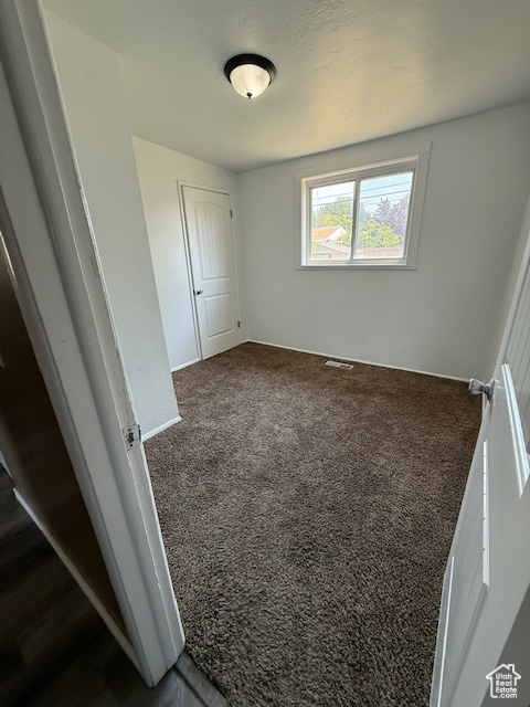 Unfurnished bedroom featuring dark colored carpet