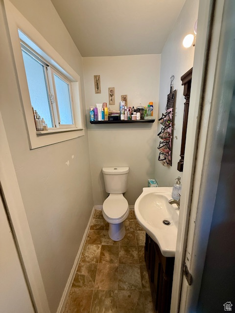 Half bath featuring baseboards, vanity, and toilet