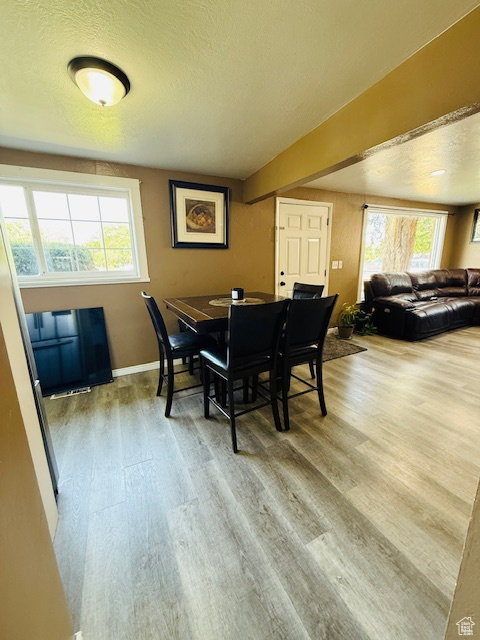 Dining space with wood finished floors, plenty of natural light, and a textured ceiling