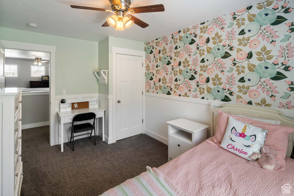 Bedroom featuring a wainscoted wall, ceiling fan, wallpapered walls, and dark carpet