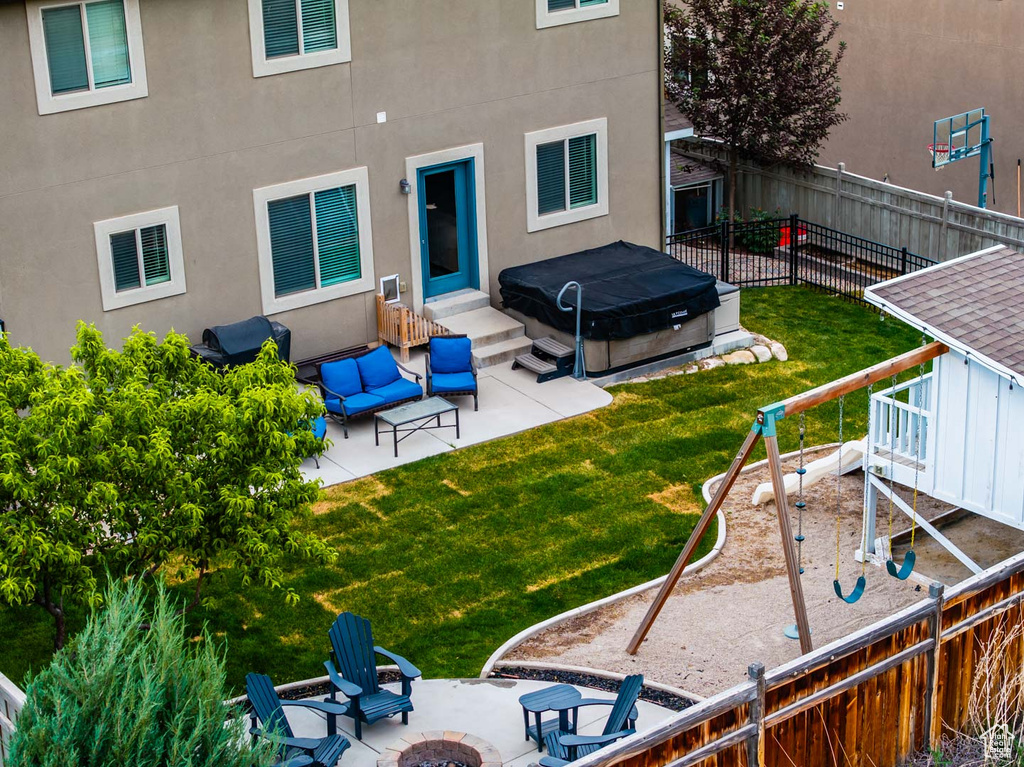 Rear view of property featuring an outdoor fire pit, a patio area, stucco siding, and a hot tub
