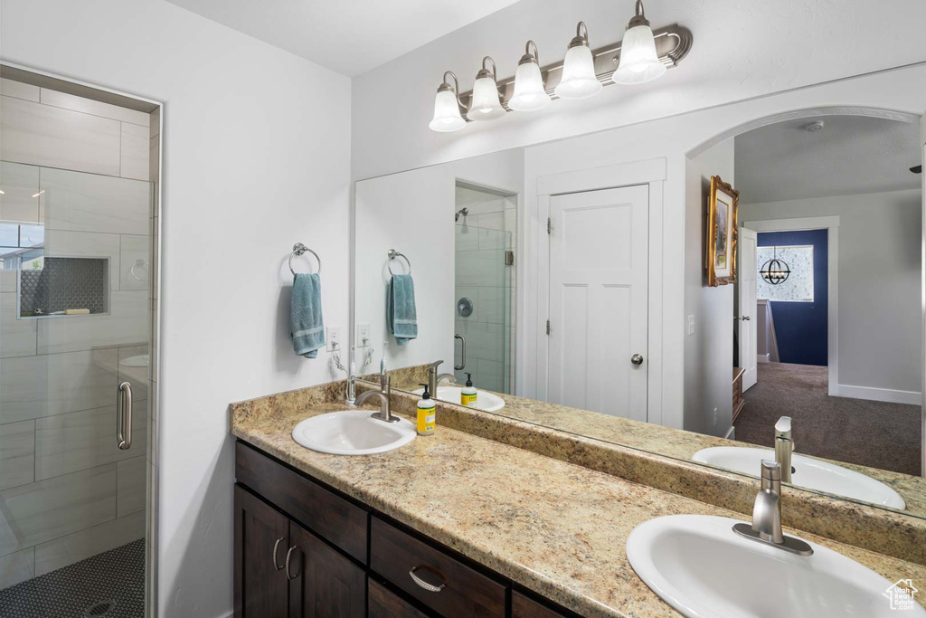 Bathroom with a sink, baseboards, a stall shower, and double vanity