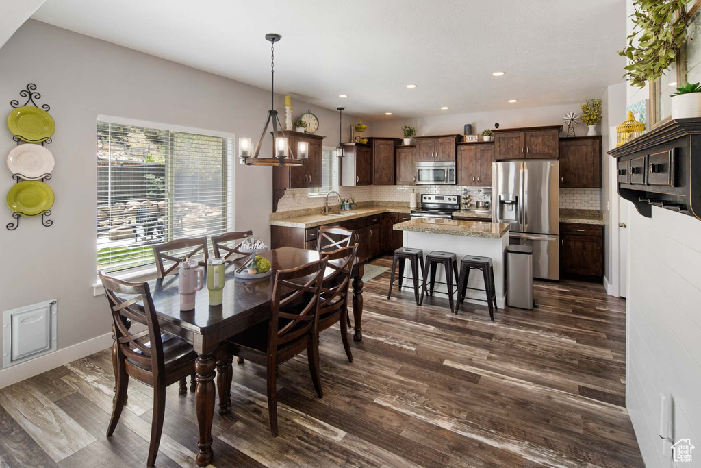 Dining room featuring baseboards, a notable chandelier, recessed lighting, and dark wood-type flooring