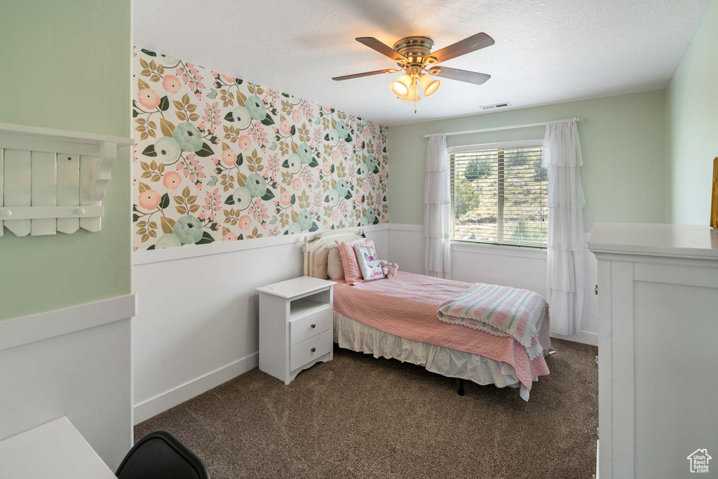 Carpeted bedroom featuring visible vents, wainscoting, baseboards, ceiling fan, and wallpapered walls