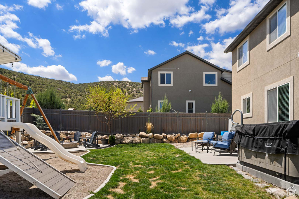 View of yard featuring a patio, a fenced backyard, an outdoor living space with a fire pit, and a mountain view